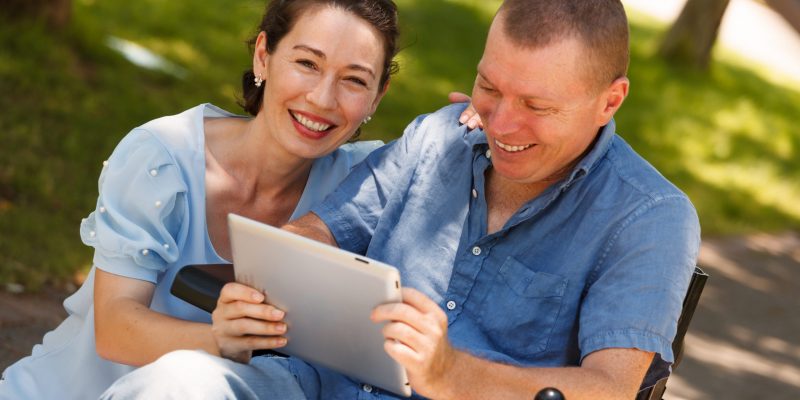 Disabled Man with his wife having fun while using tablet at the
